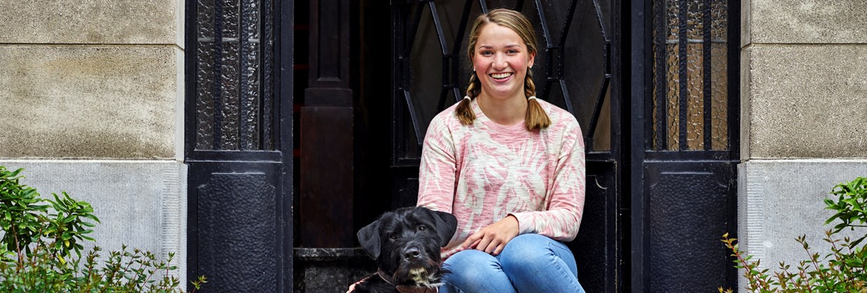 Emma, a vaccine patient in Belgium sitting on a stage with a dog