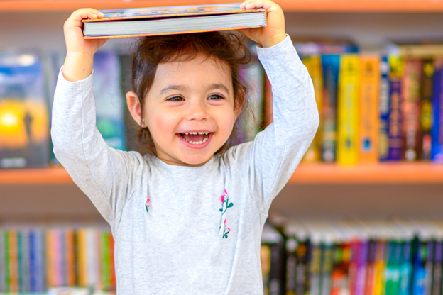 Vediamo una bimba sorridente con un libro in testa.