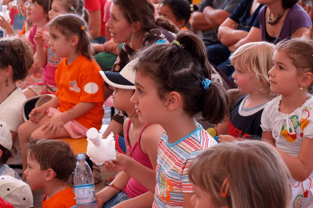 Vediamo un gruppo di bambine e bambini seguire con attenzione un racconto.