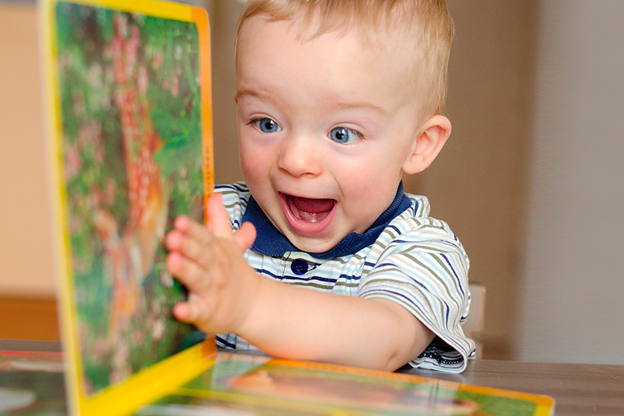 Vediamo un bambino felice giocare con delle pagine di un libro.