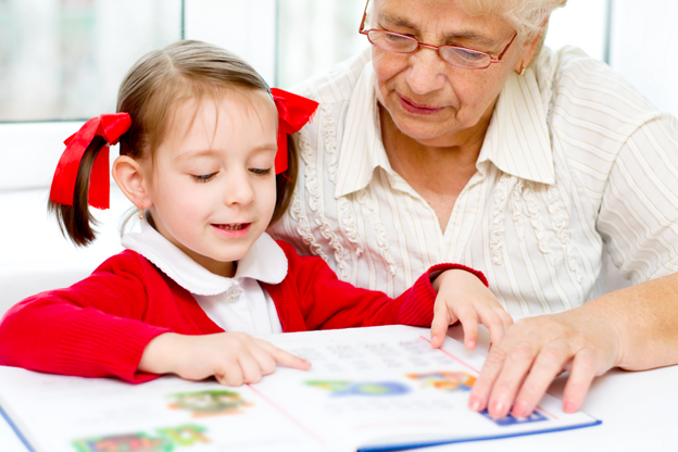 Vediamo una nonna accompagnare la nipote nella lettura di un libro.